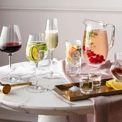 Glazen en kannen uit de Rose Garden collectie van Villeroy & Boch op een ronde marmeren tafel met drankjes en citrusvruchten.