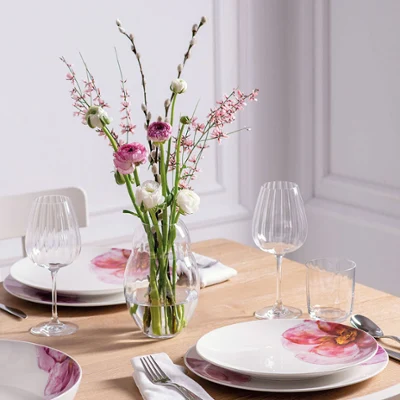 Une table de salle à manger moderne dressée pour quatre personnes avec une élégante vaisselle Rose Garden de Villeroy & Boch et un vase de fleurs de la collection Rose Garden.