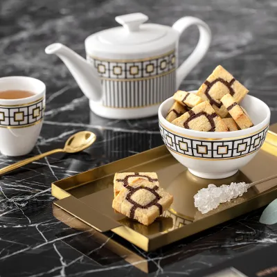 Elegant MetroChic tea set with a teapot and a cup on a gold tray, on a marble table.