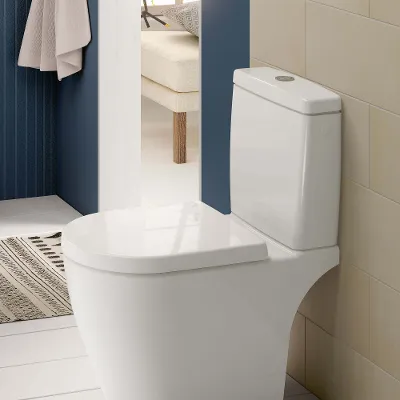 Een wit staand toilet met reservoir in een schone badkamer met beige en blauwe muren.