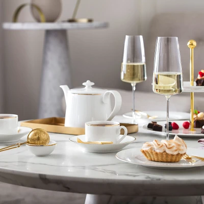 Elegant afternoon tea set-up with desserts and champagne on a marble table, served on Château Septfontaines dinnerware and MetroChic glasses.