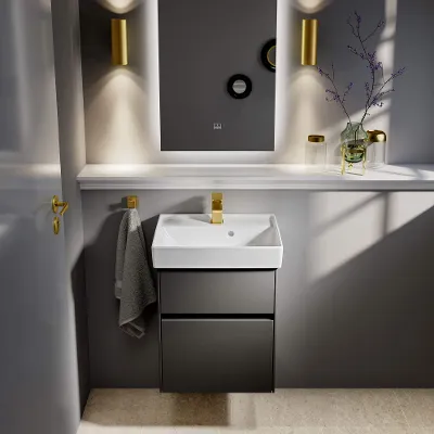 Un lavabo blanc Collaro avec des accessoires dorés et un miroir lumineux.