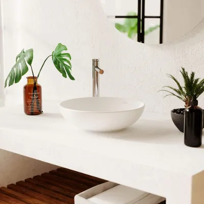 Un plan de toilette moderne avec une vasque à poser Loop & Friends blanche et une robinetterie à côté de plantes décoratives disposées dans des vases orange et noir