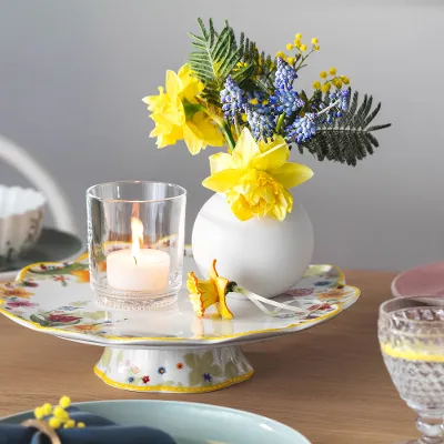 Ein Spring Awakening Kuchenständer mit Teelicht und kleinem Blumenarrangement sowie Boston Gläser von Villeroy & Boch.