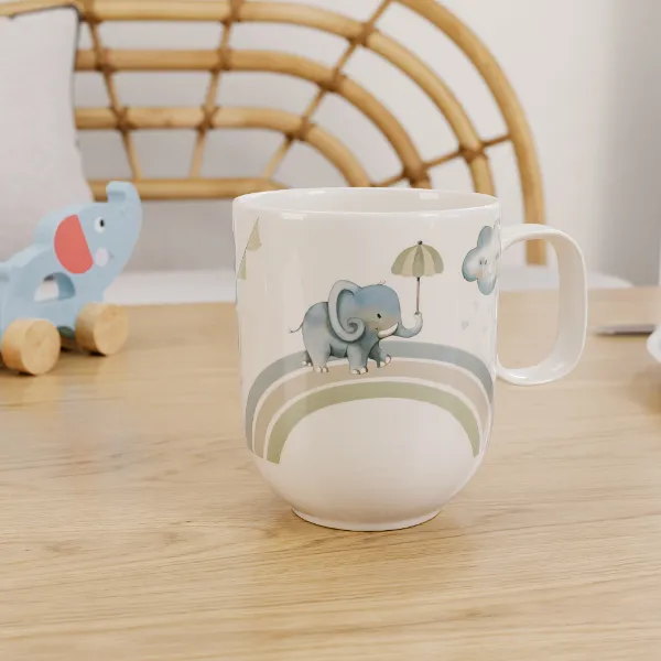 Une tasse avec un motif d’éléphant Boho Kids Walk like an elephant sur une table en bois avec un jouet en forme d’éléphant en arrière-plan.