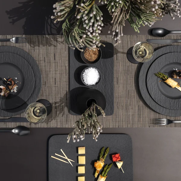 A modern dining table setting with Manufacture plates A modern dining table with two place settings, each with Manufacture plates, cutlery, napkins, starters and glasses.