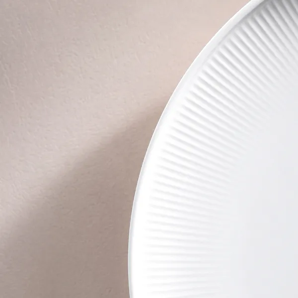 Gros plan sur le fin relief de l’assiette plate blanche Afina de Villeroy & Boch.