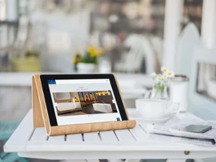 A tablet on a wooden stand displays interior fittings from Villeroy & Boch as well as a cup, a saucer, a smartphone and the ‘Download brochures’ service.