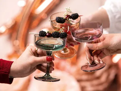 like. champagne glasses with berries A group of people holds like. champagne glasses with berries in them.