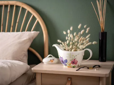Théière Mariefleur avec des fleurs séchées sur une table de nuit Une théière Mariefleur utilisée en guise de décoration avec des fleurs séchées sur une table de nuit.