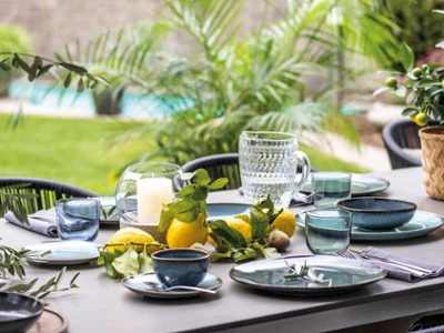 An outdoor table setting with blue and green plates from the Lave collection An outdoor table setting with blue and green plates from the Villeroy & Boch Lave collection, with candles and glasses and a lemon centrepiece.