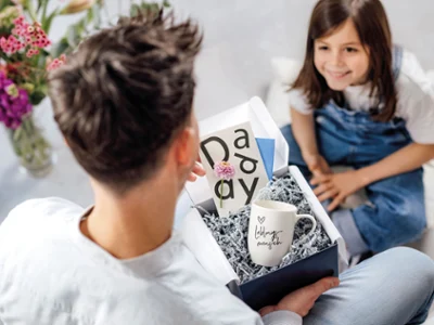 Gift of a ‘Lieblingsmensch' coffee cup in a living room Girl in a living room handing her father a gift box with a 'Lieblingsmensch' coffee cup.