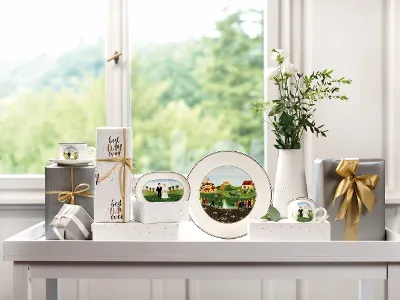 Stoviglie Design Naif decorate davanti a una finestra Un piatto Design Naif di Villeroy & Boch si trova su un tavolo addobbato con un vaso di fiori, regali decorati e cornici davanti a una finestra con vista sulla natura.