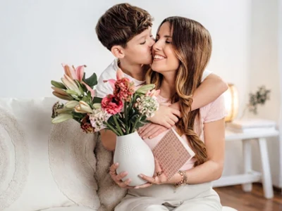 Mother holding a Manufacture Collier white porcelain vase, showcasing modern textured design with a colorful floral arrangement.