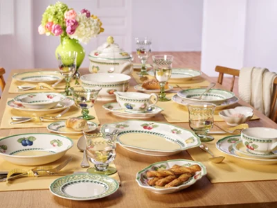 French Garden dining room table A beautifully arranged table featuring plates, cups, and bowls, prepared for dining.