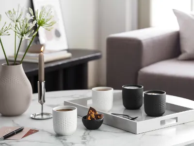 An elegant coffee table in a living room with Manufacture coffee mugs Elegant coffee table in a living room with Manufacture coffee mugs, candles, vases and a tray with cups and snacks.