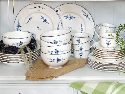 Stacked blue floral tableware—including bowls, plates, and cups—neatly arranged on a shelf.