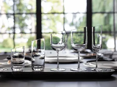 New Moon Glasses on tray Five empty glasses of different shapes are lined up on a table in front of a window.