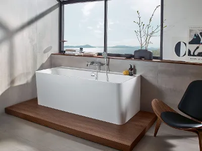 Vasca da bagno Collaro bianca in un bagno moderno con vista mare Bagno moderno con vasca rettangolare free-standing Collaro su piattaforma in legno e ampia finestra con vista sul mare.