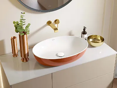 Artis washbasin in Rust in a modern bathroom A modern, orange-white washbasin in a bathroom with gold taps and decorative accessories