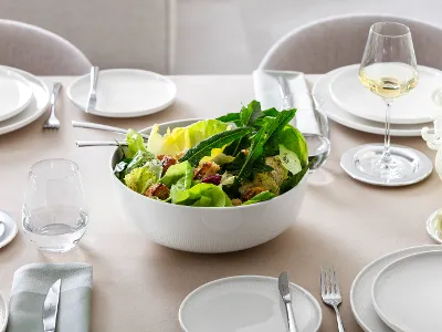 Ciotola bianca Afina con insalata Ciotola grande da portata Afina di Villeroy & Boch, riempita di insalata, su una tavola imbandita.