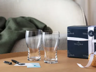 Purismo-ølglass med gaveemballasje To Purismo-ølglass fra Villeroy & Boch som gave med kort, fyllepenn og gaveeske i bakgrunnen.