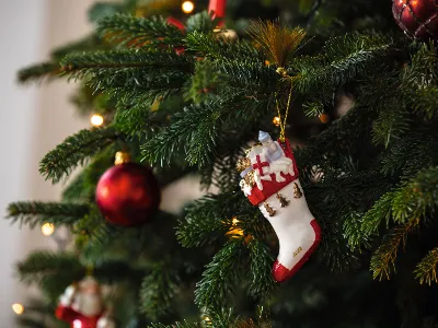 Decorazione a calza sull'albero di Natale Un albero di Natale decorato con luci, lampadine rosse e una decorazione a calza di Villeroy & Boch