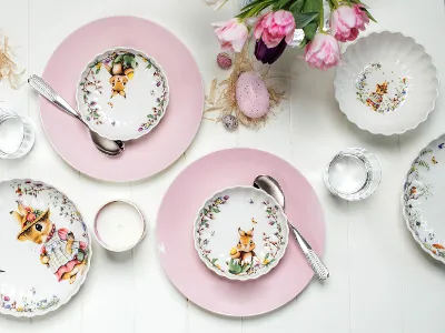 Des assiettes Spring Fantasy et Rose Garden avec des compositions florales printanières Une décoration de table sur le thème de Pâques avec des assiettes décorées Spring Fantasy et des assiettes Rose Garden servant d’assiettes de présentation ainsi qu’une composition florale.