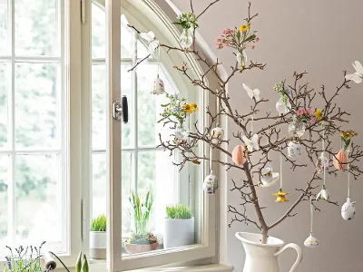 Tree branch decorated with Villeroy & Boch Easter ornaments on a windowsill Springtime interior design with a decorative tree branch with Villeroy & Boch Easter ornaments on the windowsill, together with plants and a white jug on a tray.