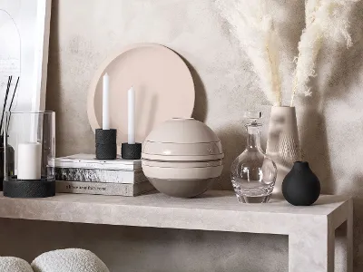 Beige La Boule with decorative objects in front of a light-coloured wall Modern table decoration with decorative items in neutral shades, including candles, a transparent decanter and a vase with pampas grass, along with a modern La Boule, in front of a wall with a light-coloured texture.