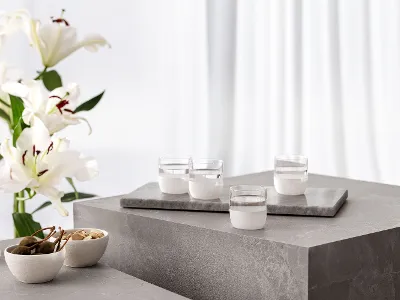 Four white Manufacture water glasses on a concrete table, white lilies in a vase and Manufacture bowls with snacks.