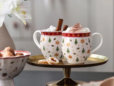 Deux tasses festives Toy's Delight Deux tasses Toy's Delight festives avec de la crème fouettée et des bâtons de cannelle sur un plateau, à côté de biscuits et d'un vase de fleurs.