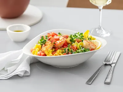 Piatto Vapiano di Villeroy & Boch riempito con pasta e insalata Piatto Vapiano di Villeroy & Boch su un tavolo di legno con insalata di pasta Un bicchiere da vino e posate di Villeroy & Boch sul tavolo