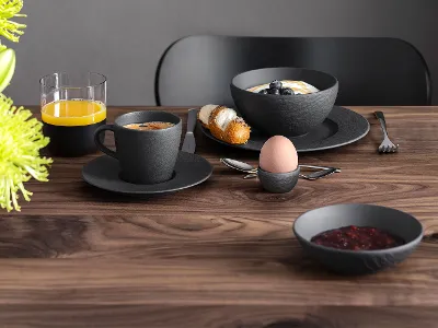 Manufacture breakfast set on a wooden table A breakfast set with coffee, juice, a croissant, jam and a soft-boiled egg on a wooden table, green flowers are visible.