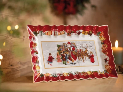 Festive ceramic tray with red scalloped edges, depicting a winter scene with Santa, children, and reindeer, surrounded by gifts. Cozy ambiance.
