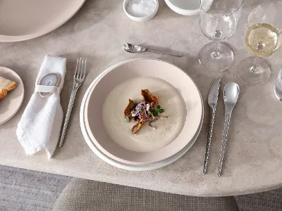 Plates and flatware from Villeroy & Boch with cream soup A table set with NewMoon plates and flatware from Villeroy & Boch with a cream soup.
