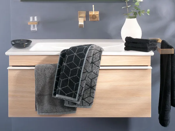Schwarze One Handtücher auf einem Waschbeckenunterschrank Ein Waschbecken mit schwarzen Handtüchern aus der Kollektion One von Villeroy & Boch und einem Spiegel.