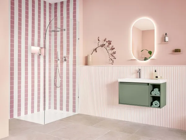 Grøn Skyla håndvask underskab på en håndvask i rosa Badeværelse Moderne badeværelse med rosa og hvidstribet bruser, ovalt spejl, væghængt håndvask og lyst trægulv.