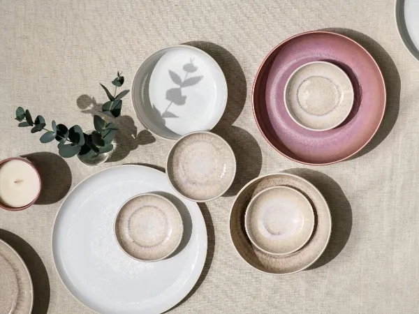 Różne talerze Crafted i Perlemor na teksturowanej powierzchni Talerze Crafted i Perlemor w pastelowych kolorach, ułożone na neutralnej, teksturowanej powierzchni.