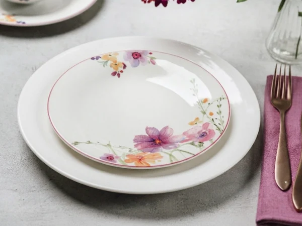 New Cottage plate paired with Mariefleur plate close-up Close-up of a New Cottage plate layred with a Mariefleur plate on a elegant table setting.