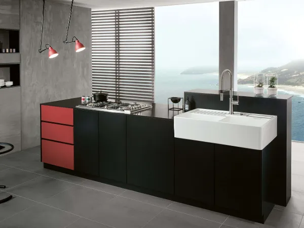Double-basin butler sink in a grey kitchen A white butler sink with double basin in a black and grey kitchen with the sea and beach in the background.