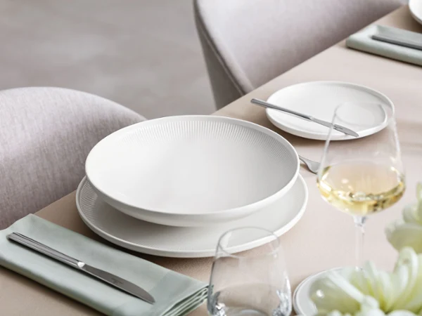 Afina soup plate on a laid table A table with a glass of wine and a table set with Villeroy & Boch Afina plates.
