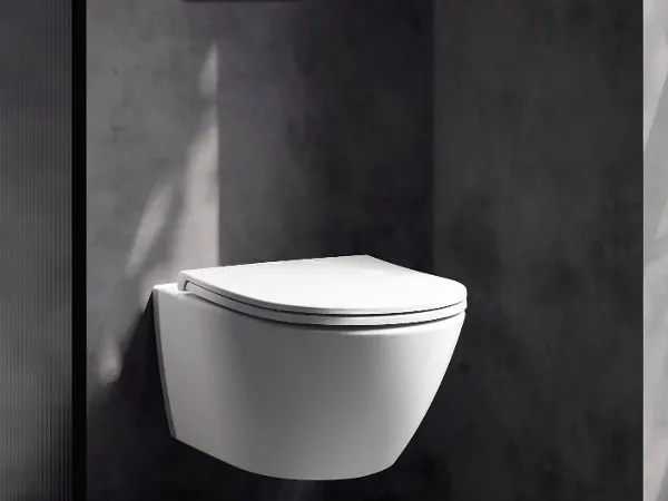 All-black style bath A Finion bath in black and white with lighting in a dark bathroom next to large windows. A patterned carpet and a small table with green towels can be seen.