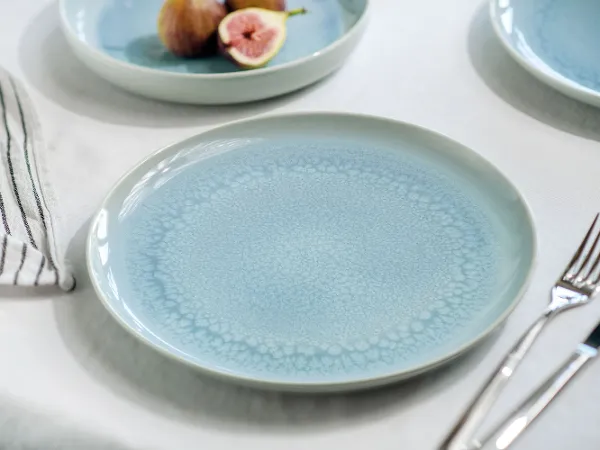 Une assiette bleue Crafted sur une table Une assiette bleue Crafted de like. by Villeroy & Boch avec des figues et une fourchette sur une table.