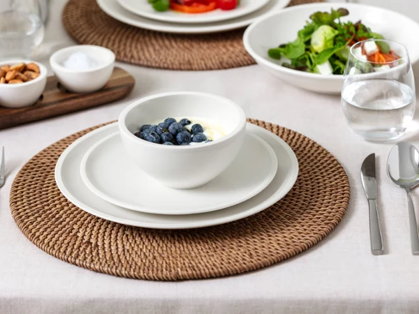 Artesano bowl on table with yogurt topped with blueberries Elegant table setting with Artesano with blueberries on yogurt and water glass.