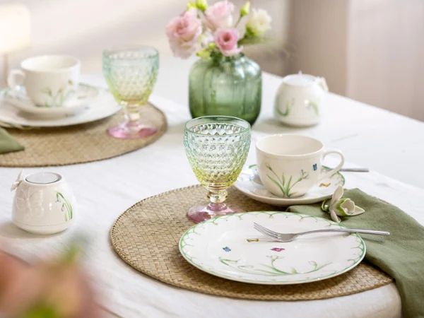 Das Set Colourful Spring von Villeroy & Boch verschönert jeden Tisch für zwei mit Tellern und Tassen mit Blumenmuster Das Set Colourful Spring von Villeroy & Boch verschönert jeden Tisch für zwei mit Tellern und Tassen mit Blumenmuster, leuchtend grünen und gelben Gläsern, rosa Blumen in einer Vase und beigen Tischsets auf einer weißen Tischdecke.