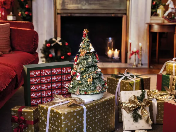 Christmas Toys Adventskalender auf einem Tisch umgeben von verpackten Geschenken Ein weihnachtlich dekoriertes Wohnzimmer mit dem Christmas Toys Adventskalender auf einem Tisch, umgeben von verpackten Geschenken, vor einem Kamin.