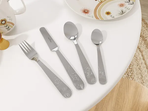 Boho Kids cutlery set with a porcelain plate in the same design A set of children’s stainless steel cutlery from the Boho Kids collection with a playful pattern, neatly arranged next to a porcelain plate with a playful animal pattern.
