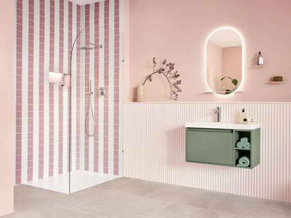 Soft green Skyla washbasin on pastel pink wall Skyla washbasin in soft green with storage space, wall-mounted against a pastel pink background and shower in white alpin