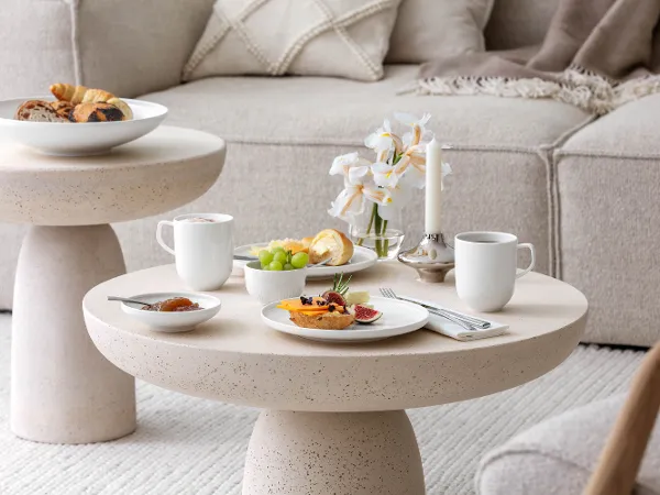Afina Geschirr mit Frühstück auf einem Couchtisch Frühstück mit Kaffee, Marmelade und belegten Brötchen auf beigefarbenem Couchtisch mit weißem Afina-Geschirr von Villeroy & Boch.